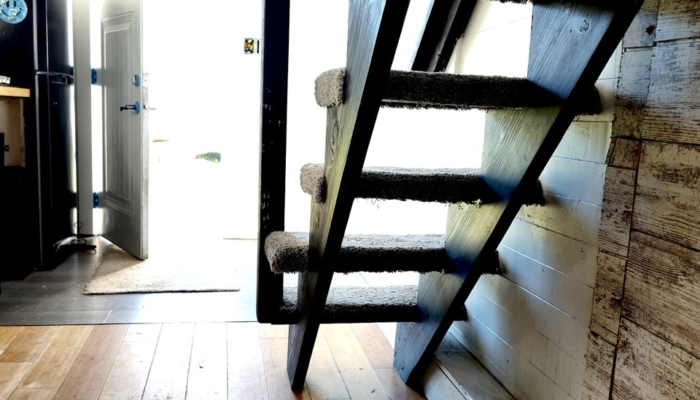 Open layout tiny house interior with stairs to loft and kitchen workspace Open layout tiny house interior with stairs to loft and kitchen workspace