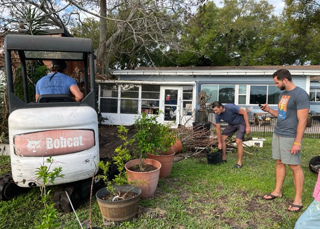 Neighbors working together to prepare soil for raised garden beds in tiny home community Neighbors working together to prepare soil for raised garden beds in tiny home community