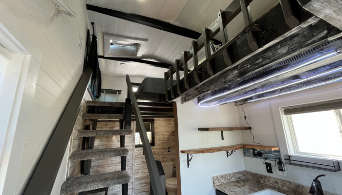 Open layout tiny house interior with stairs to loft and kitchen workspace Open layout tiny house interior with stairs to loft and kitchen workspace